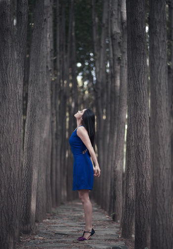 Woman standing amidst trees at forest