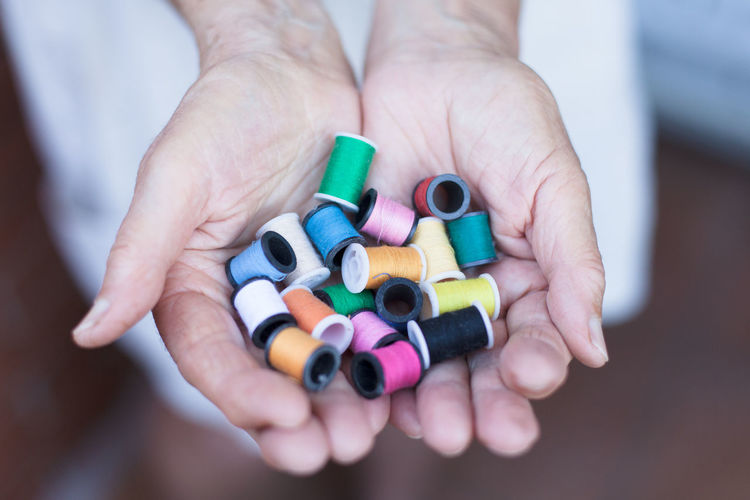Cropped image of person holding colorful spools