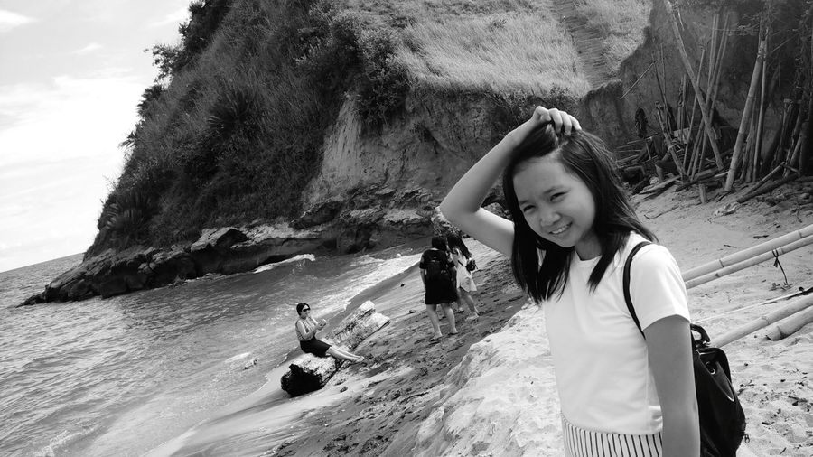 Girl with hand in hair standing on shore at pantai mahembang