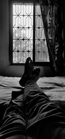 Low section of man relaxing on bed at home