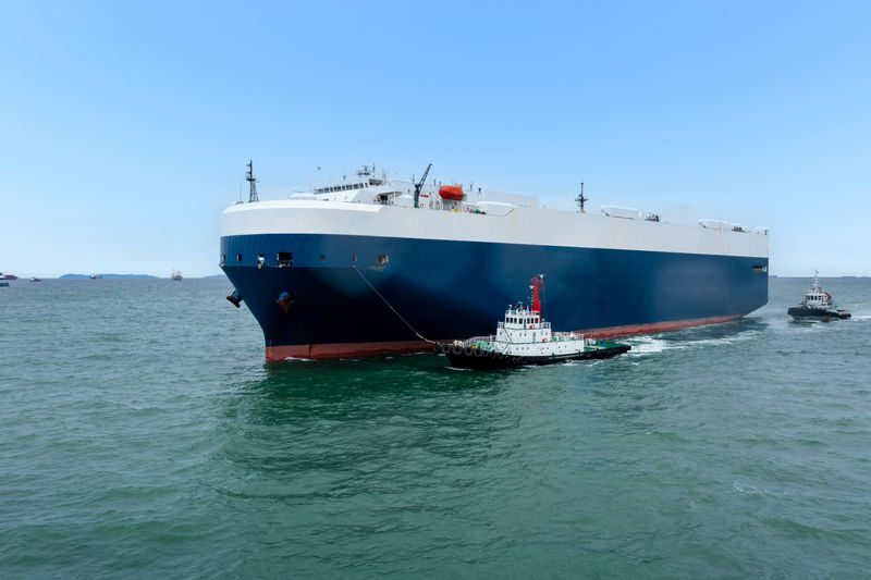 Roll-on roll-of ship loading new cars line up . automotive container carriers floating 