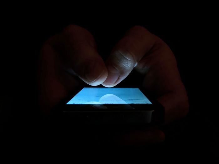 Midsection of man using mobile phone against black background