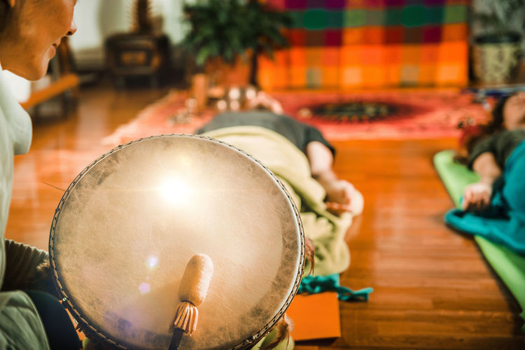 Midsection of therapist playing drum while performing music therapy at spa