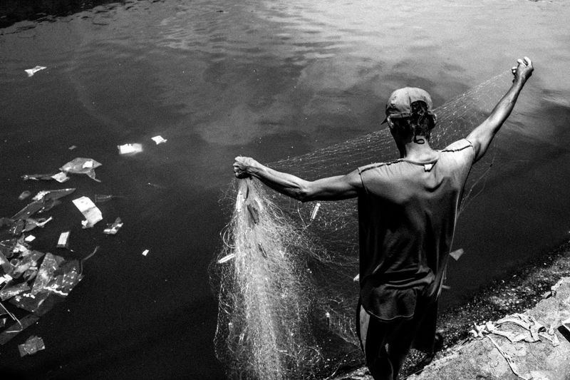 High angle view of man holding fishing net while standing at riverbank