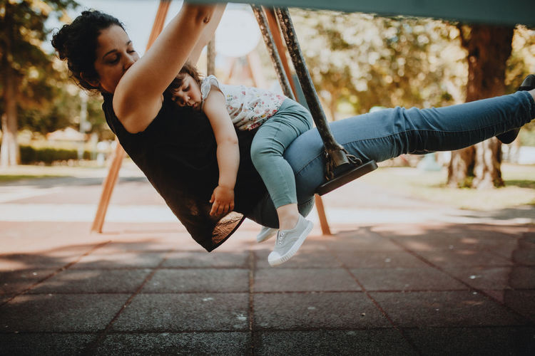 Woman with daughter swinging in park