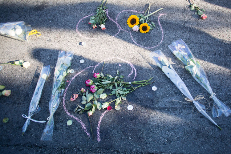 High angle view of bouquets and tea lights on chalk drawing at road after terrorist attack