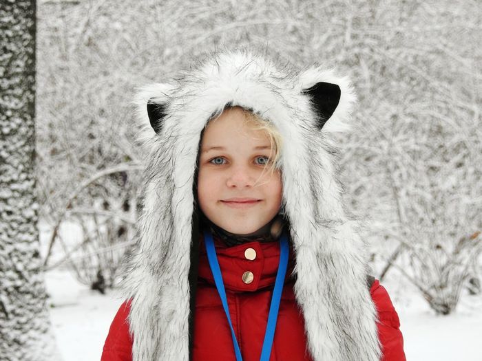 Close-up portrait of girl standing against snowcapped trees