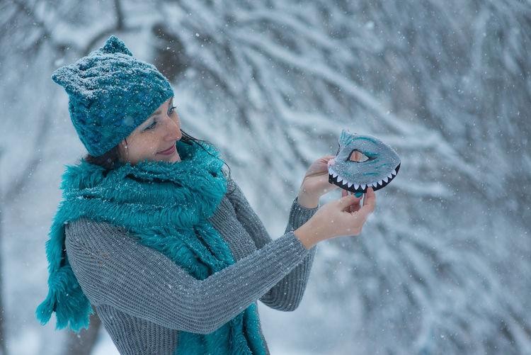 Woman holding eye mask during winter