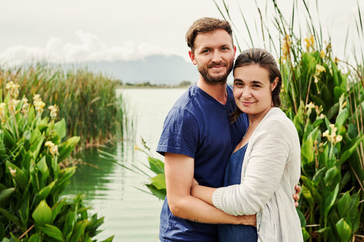 Portrait of couple embracing by lake