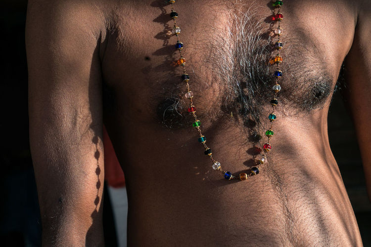 Midsection of shirtless man wearing necklace