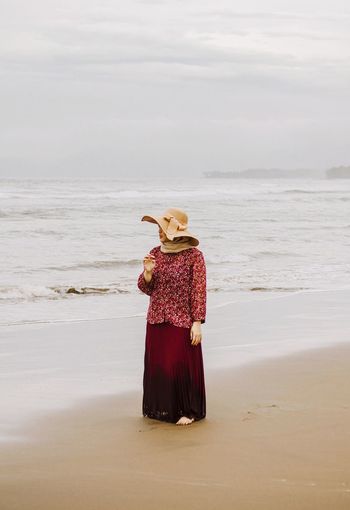 Woman standing at beach against sky