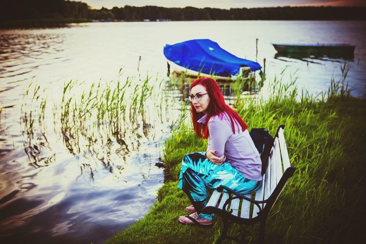 Young woman sitting on grass by lake