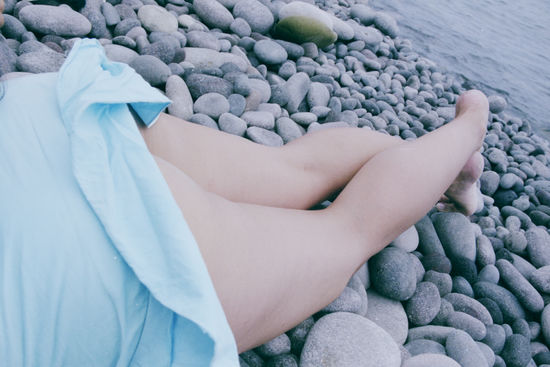 Low section of woman with pebbles at beach