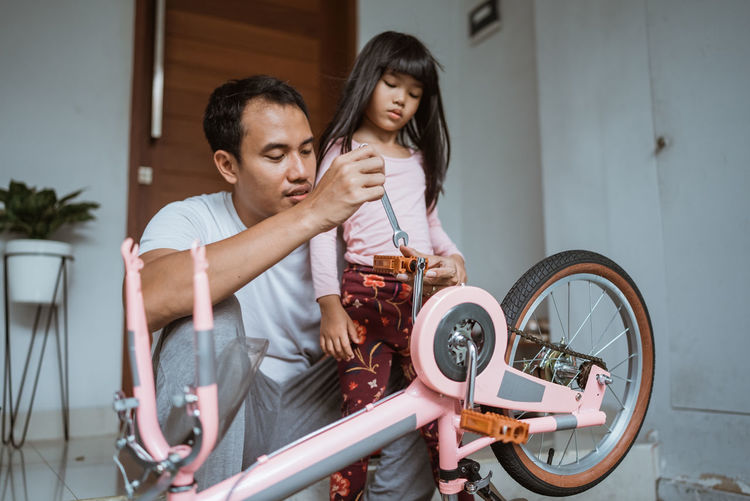 Father repairing bicycle outdoors