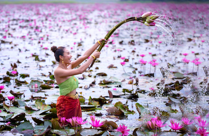 Woman holding pink flower in lake