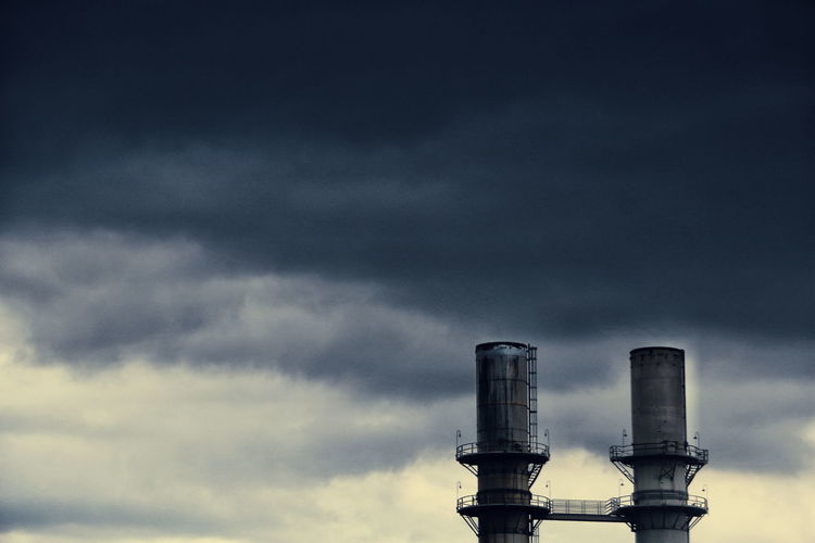 Low angle view of silos against cloudy sky at dusk
