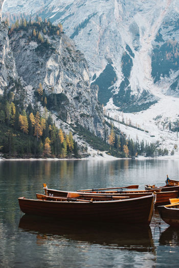 Boats moored on lake against snow covered mountain