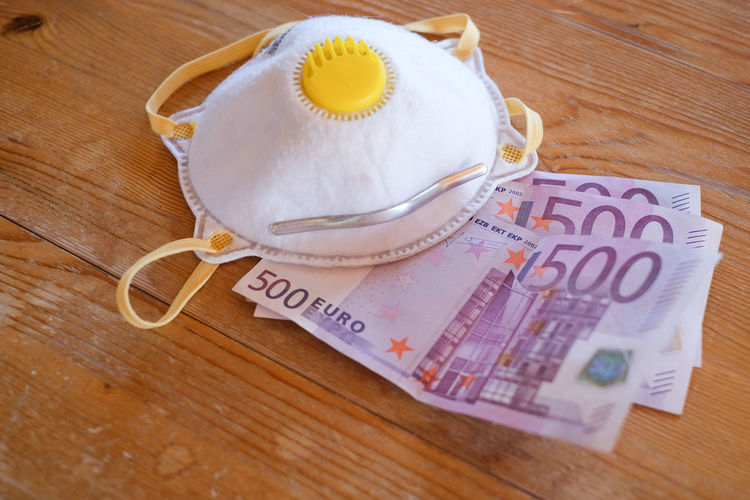 Close-up of three 500 euro bills and ffp2 mask lying on table