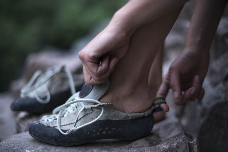 Low section of female hiker wearing shoes on rock