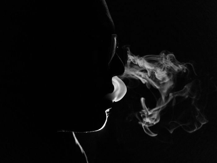 Close-up side view of person smoking against black background