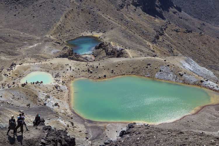 People hiking next to iconic emerald lakes at tongariro crossing trail