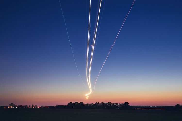 Light trails of airplane during landing at airport after sunset.