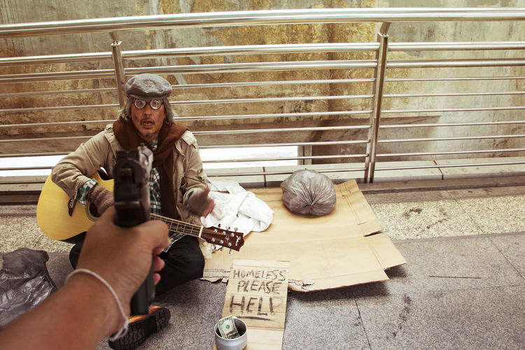 Cropped image of criminal shooting beggar