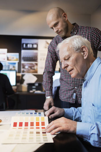 Businessmen choosing color from swatch in office