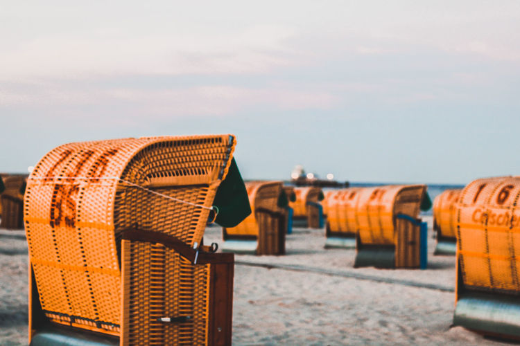 Hooded chairs on beach against sky