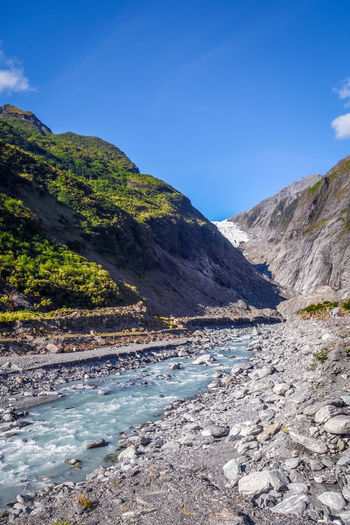Scenic view of river amidst mountains against blue sky
