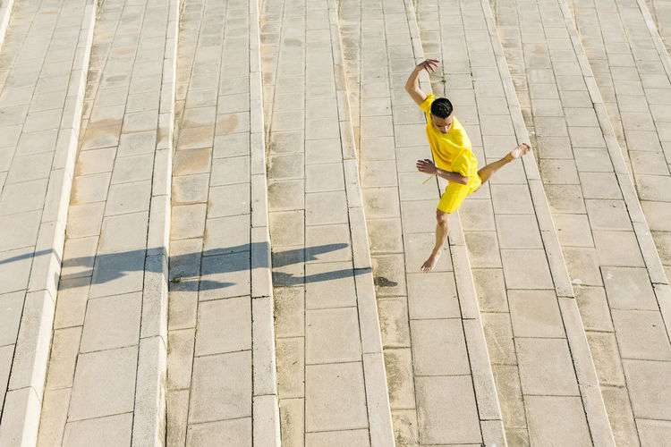 Young man jumping while dancing on steps during sunny day