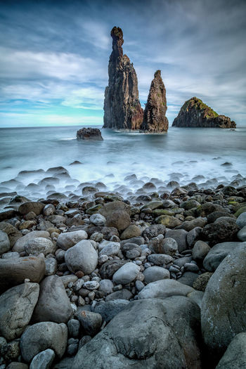 Scenic view of sea by rock formation against sky