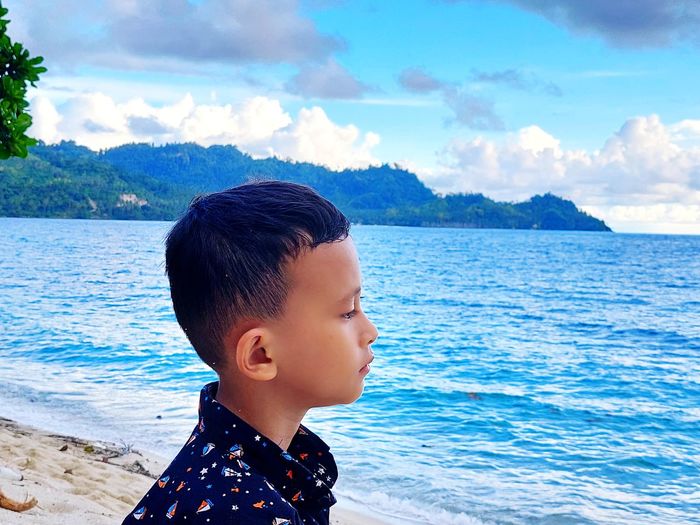 Portrait of boy looking at sea against sky