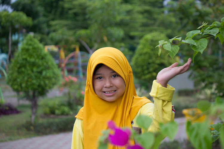 Portrait of smiling woman standing against yellow flowering plants