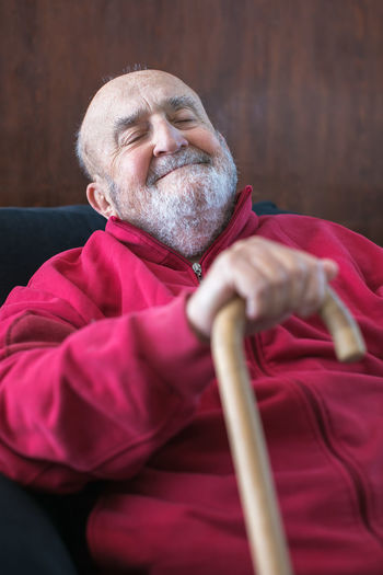 Elderly man sitting with walking stick in his hand
