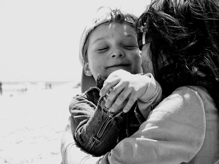 Close-up of mother hugging son at beach against sky