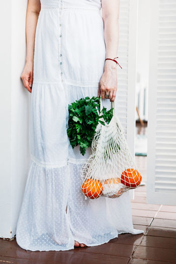 Low section of woman holding fruits in bag