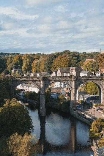 Arch bridge over river in city against sky