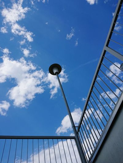 Low angle view of street light by railing against sky