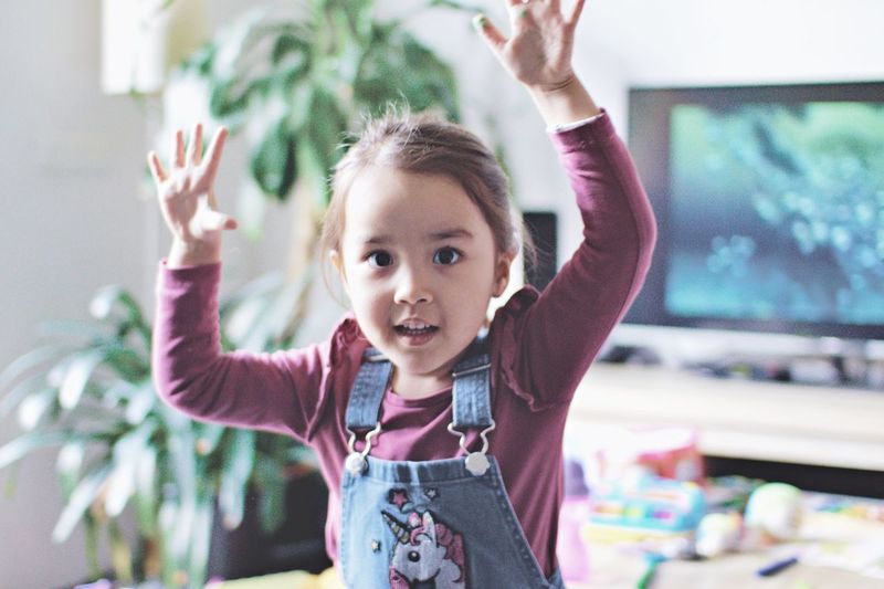 Portrait of cute girl with arms raised