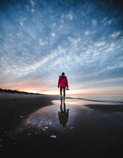 Rear view of woman on bicycle at beach during sunset