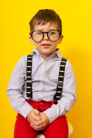Portrait of boy wearing sunglasses against yellow background