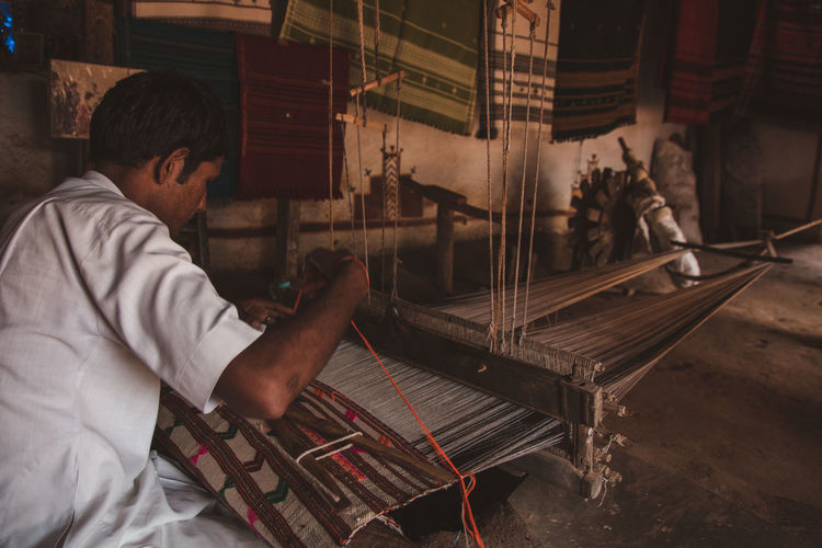 Side view of man working as a weaver
