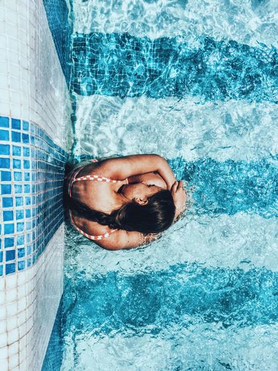 Overhead view of girl sitting in swimming pool