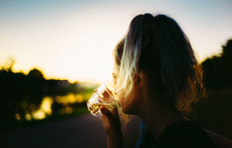 Close-up of woman drinking whiskey against sky
