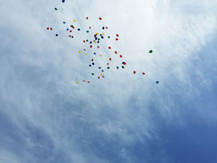 Low angle view of colorful balloons flying against sky