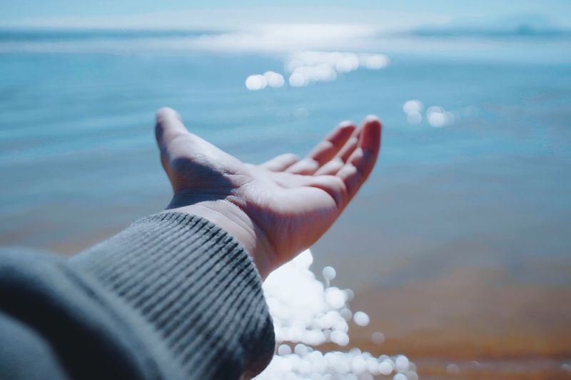 Cropped hand of woman reaching sea