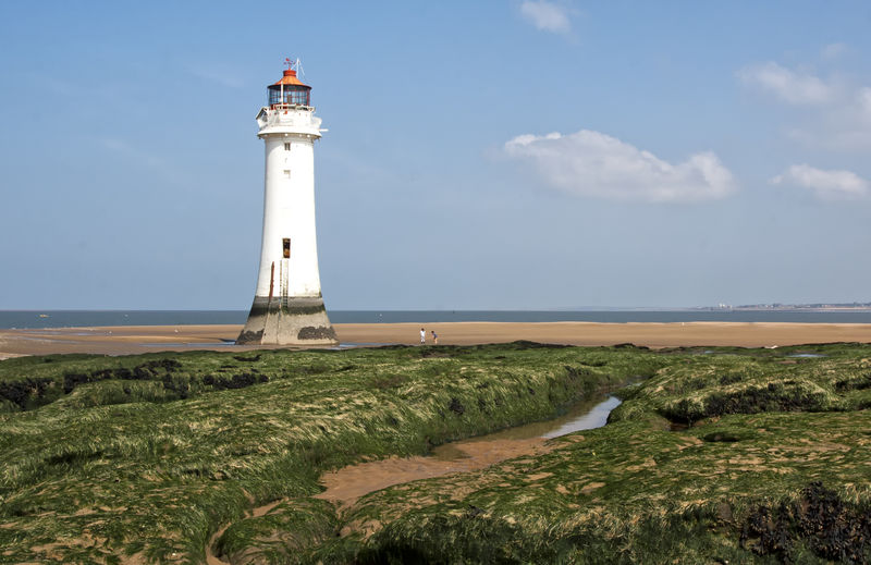 Low angle view of lighthouse at beach against sky on sunny day