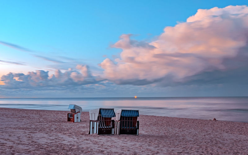 Lifeguard chair on beach against sky during sunset