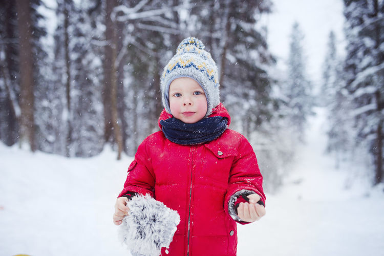 Kid red coat in winter snowy forest